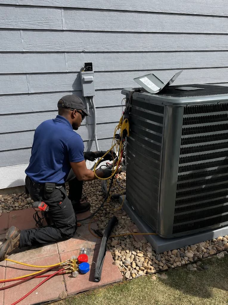 An ASAP Heating and Cooling technician connecting gauges to an outdoor air conditioning condenser