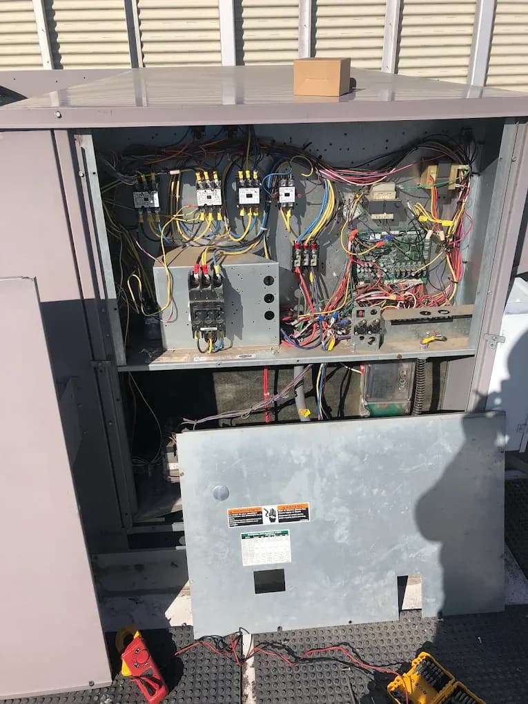 An HVAC unit with its access panel removed, exposing the control board and wiring during a diagnosis